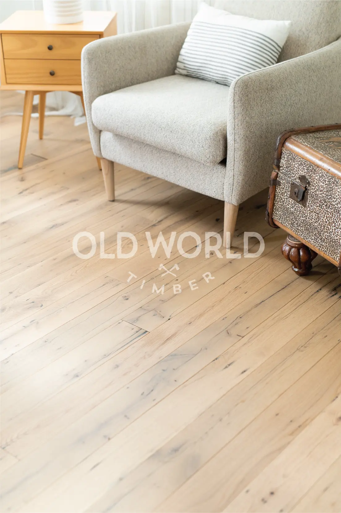 Character-marked reclaimed oak flooring beneath a cozy chair, highlighting blackened nail holes and historic grain patterns.
