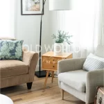 Light reclaimed oak flooring beneath a neutral armchair and natural wood side table, emphasizing timeless warmth and durability.
