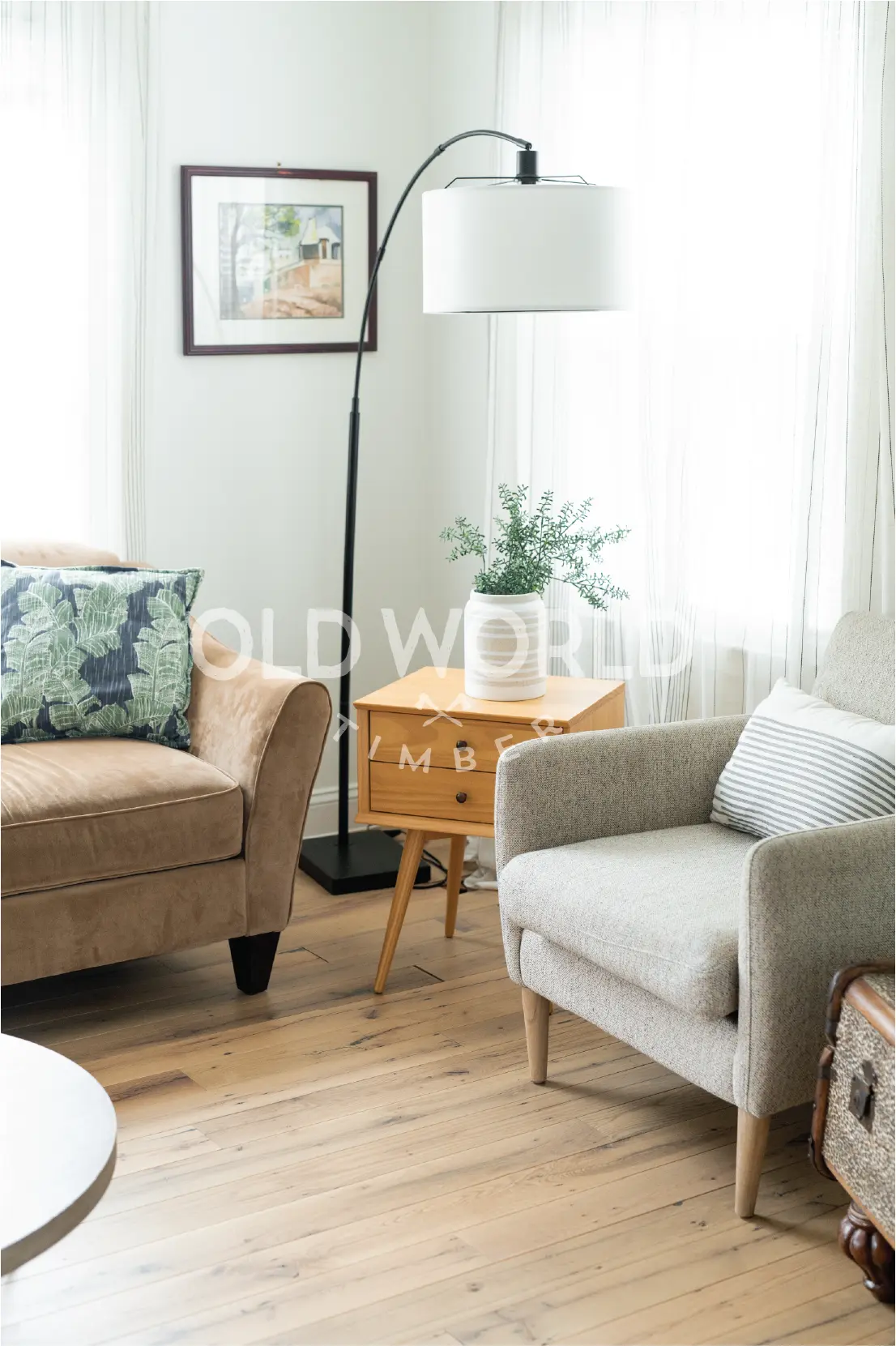Light reclaimed oak flooring beneath a neutral armchair and natural wood side table, emphasizing timeless warmth and durability.