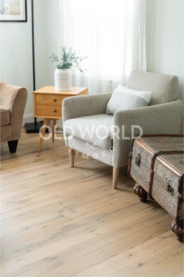 Light-filled room with a cozy reading chair and vintage chest over reclaimed oak flooring sourced from old warehouses.