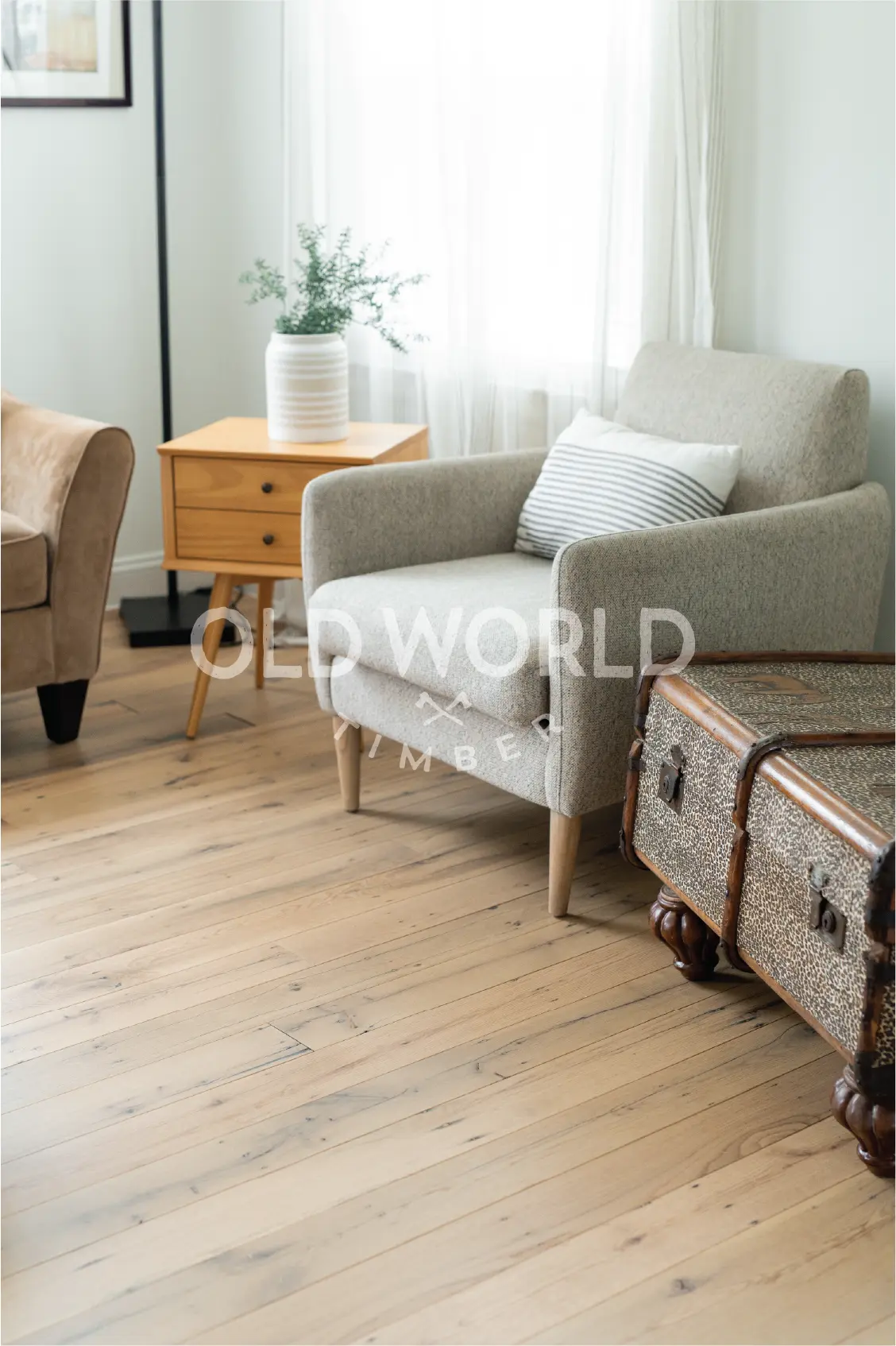 Light-filled room with a cozy reading chair and vintage chest over reclaimed oak flooring sourced from old warehouses.