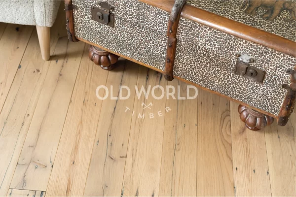 Close-up of vintage leopard-print chest sitting on light reclaimed oak flooring, showing wormholes and saw marks from its former life in factories.