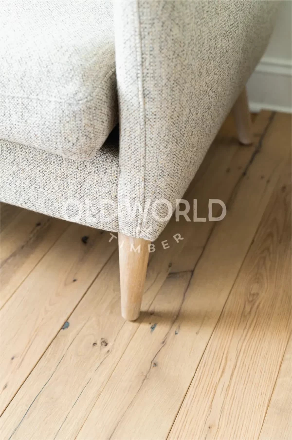 Reclaimed white oak engineered flooring with clean face finish and natural imperfections, installed alongside light-colored furniture in a modern room.