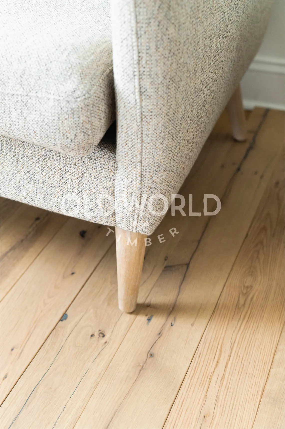 Reclaimed white oak engineered flooring with clean face finish and natural imperfections, installed alongside light-colored furniture in a modern room.