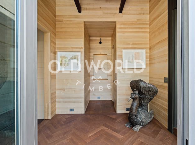 Oak Rift and Quartered wood flooring in a contemporary entryway with natural wood paneling and decorative sculpture.