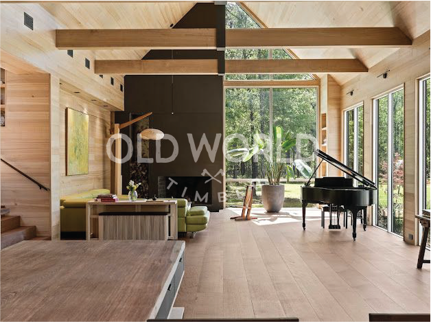 Wide-plank rift and quartered oak flooring in a bright living room with floor-to-ceiling windows and exposed wood beams.
